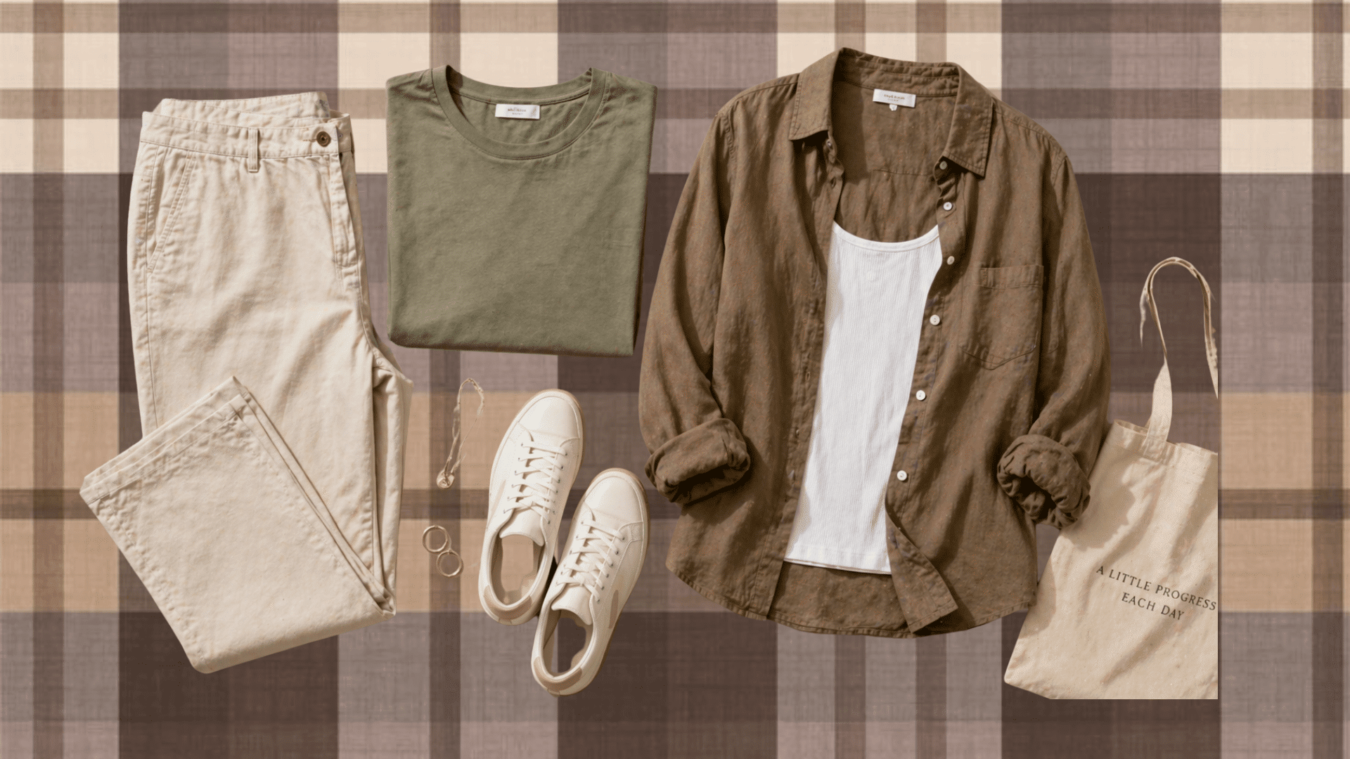 Flat lay of neutral outfit beige pants, olive tee, brown shirt over white tank, white sneakers, tote bag and accessories on plaid background