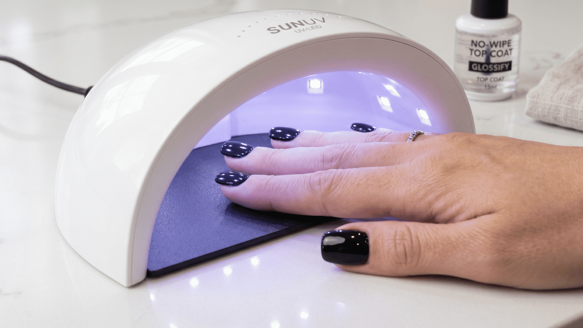 nails under a UVLED lamp with a glossy no-wipe top coat applied