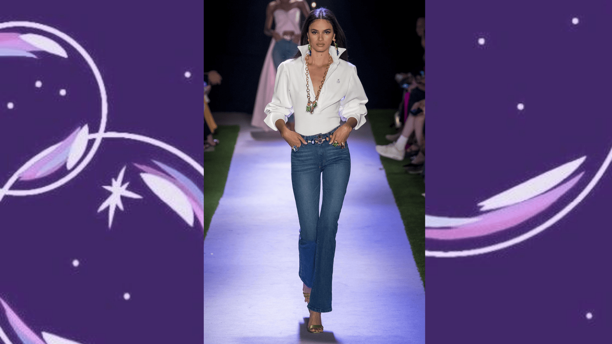 runway model in white oversized shirt with dark bootcut jeans, bold jewelled belt and gold heels