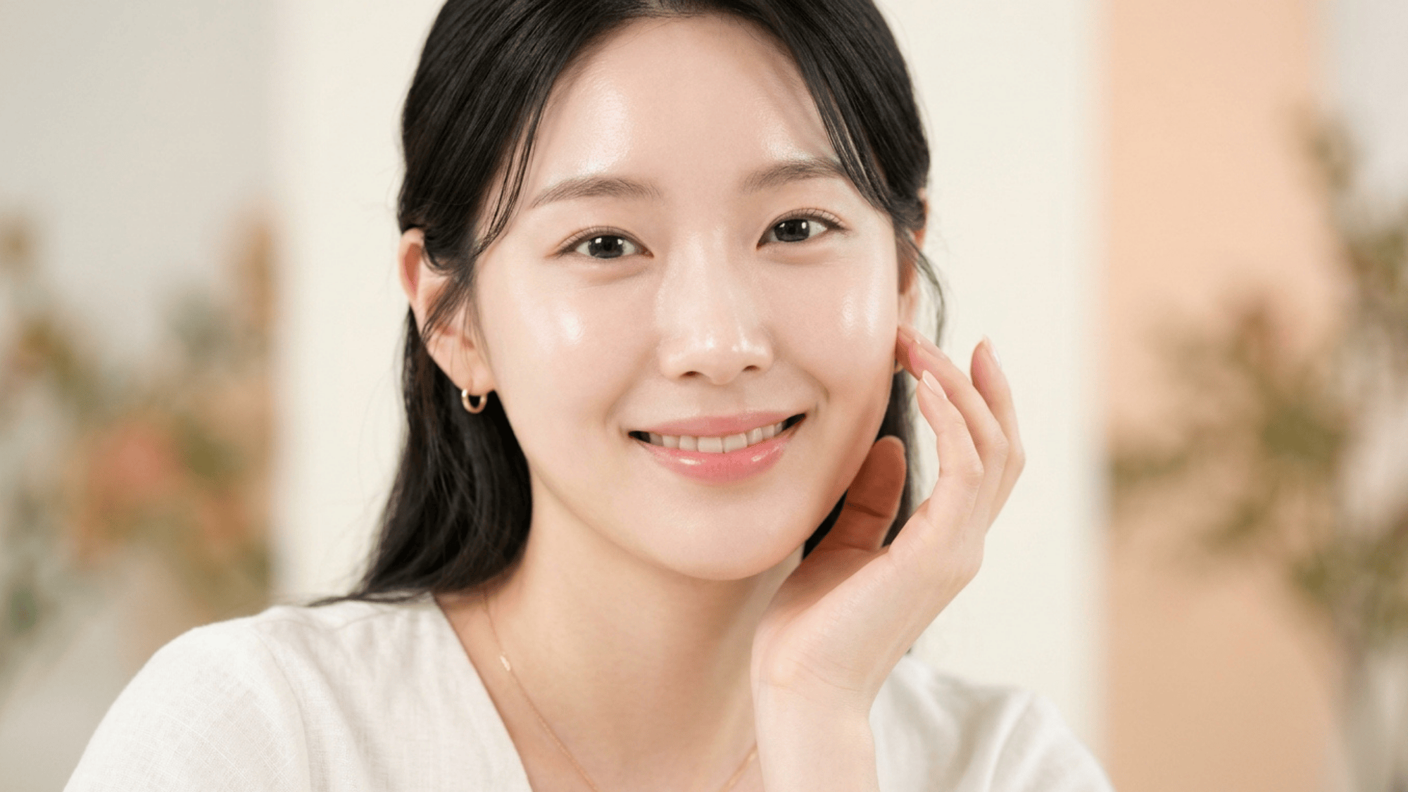 smiling woman with healthy glowing skin minimal makeup and soft neutral background