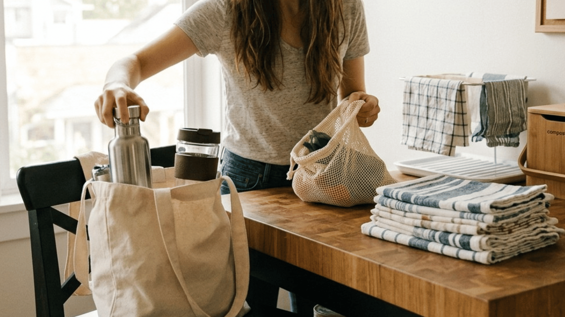 woman packing reusable kit with bottle, utensils, and container in cloth bag.