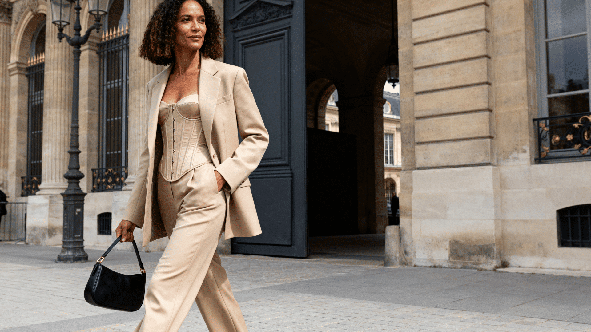 woman wearing a matching blazer and trouser co-ord set with a corset top outside a luxury hotel in a fashion district
