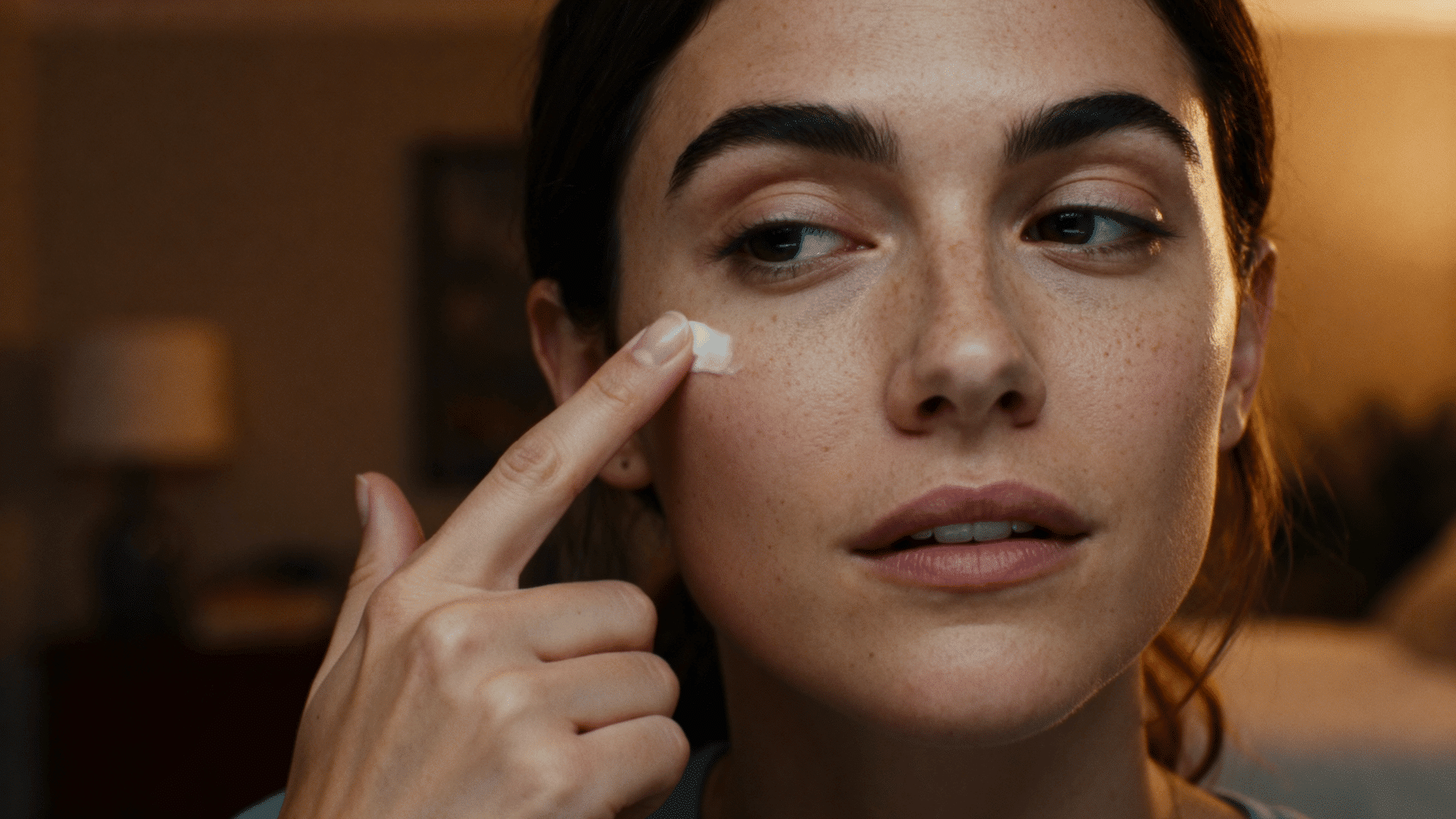woman gently applying eye cream under her eyes before bed.