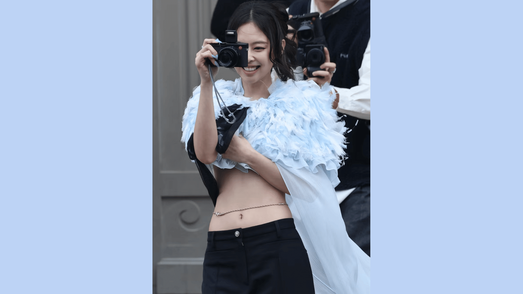 woman wearing a light blue feathered cape with a delicate gold waist chain and sheer layered outfit on a fashion runway