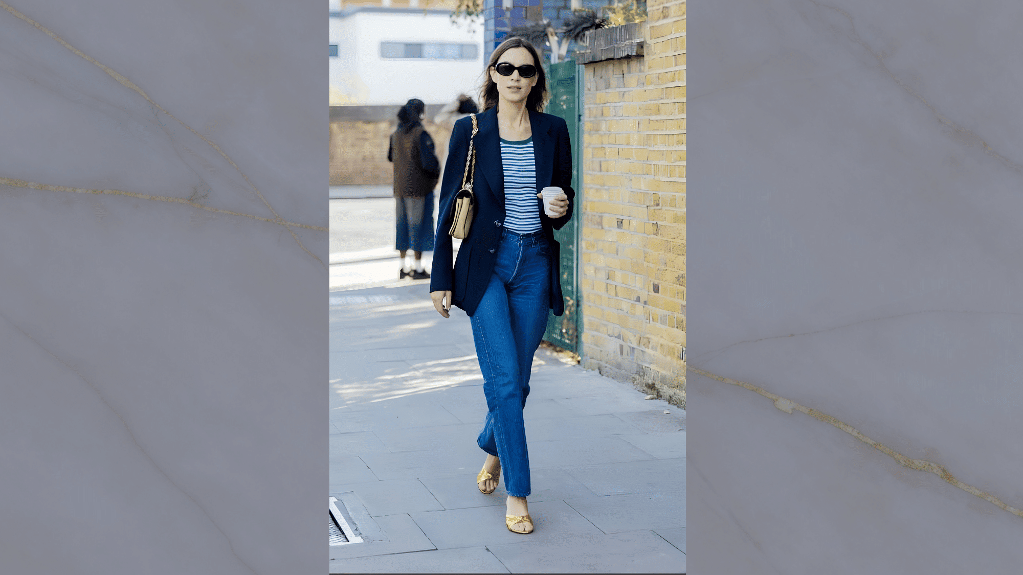 alexa chung wearing a navy blazer striped top blue skinny jeans and gold flats while carrying coffee for a smart casual street style outfit