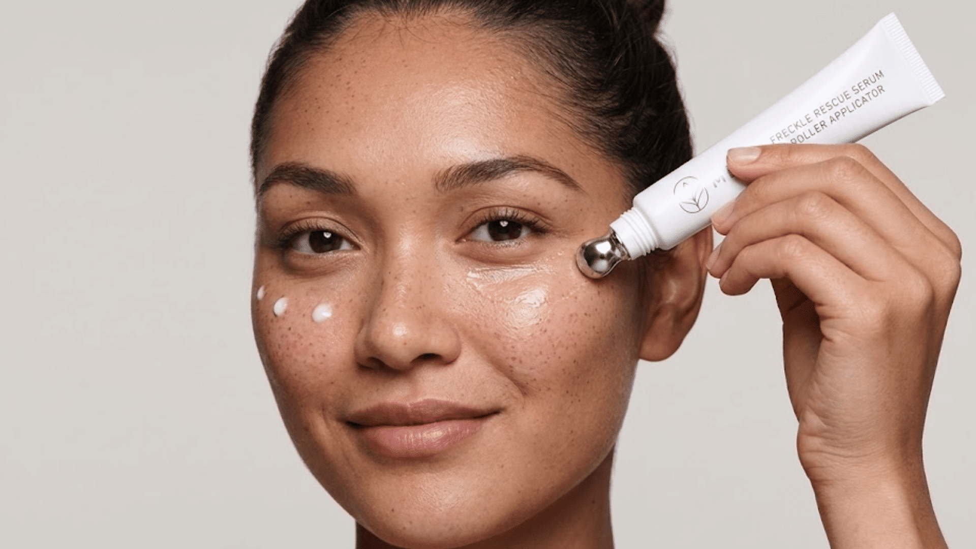 woman applying eye cream with a metal roller applicator around her under-eye area