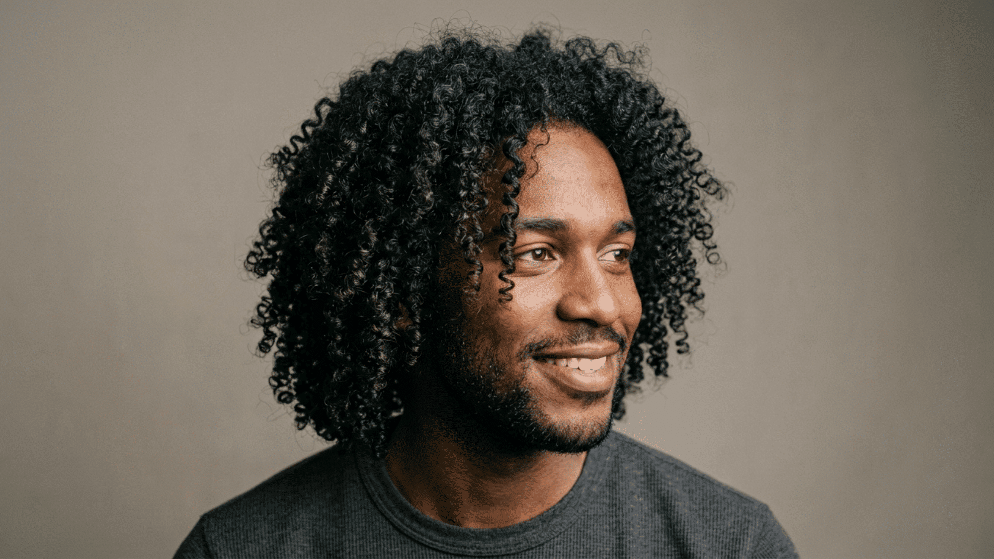 man with long defined 3c curls against neutral background
