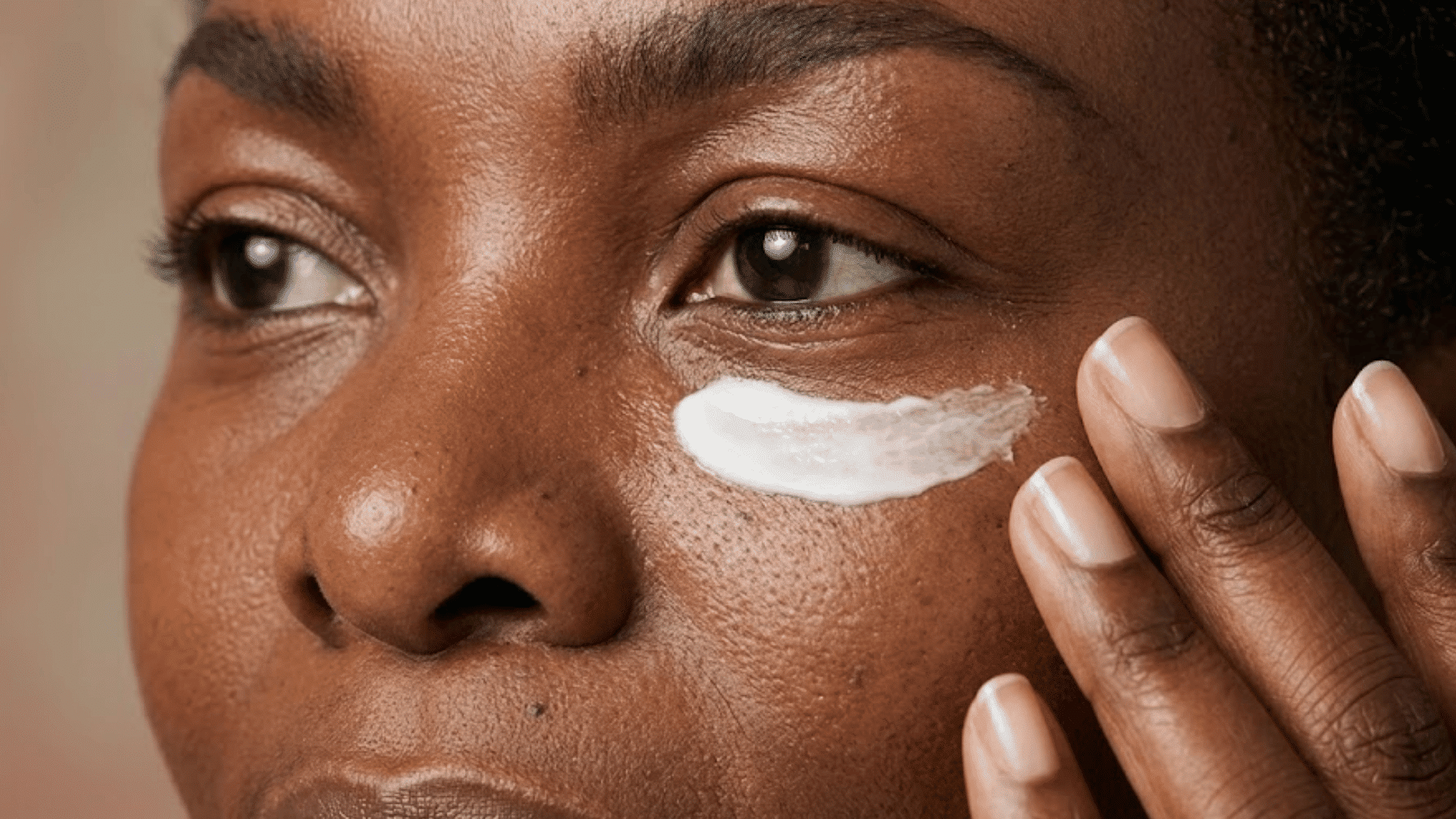 close-up of a woman applying eye cream beneath her eye to hydrate skin and soften the look of fine lines